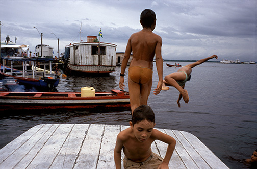 School boys in the Amazon port city of Manaus leap from fishing boats into the Rio Negro below a central city market. The Rio Negro enters the Rio Solimões at Manaus to form the Brazilian Amazon. School boys in the Amazon port city of Manaus leap from fishing boats into the Rio Negro below a central city market. The Rio Negro enters the Rio Solimões at Manaus to form the Brazilian Amazon. © Kevin Moloney, 1995
