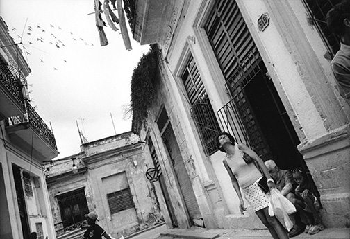Pigeons fly overhead as a Havana resident looks up to gauge the day's weather. © Kevin Moloney, 2001.